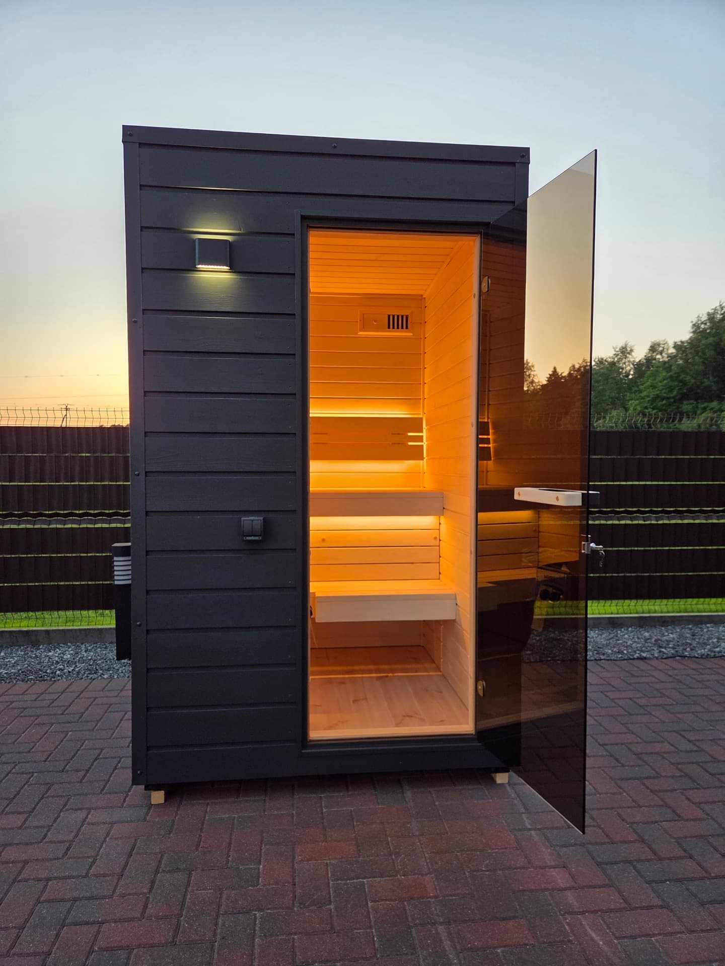 The cabin at dusk with the door swung open, both benches and the heater lit inside