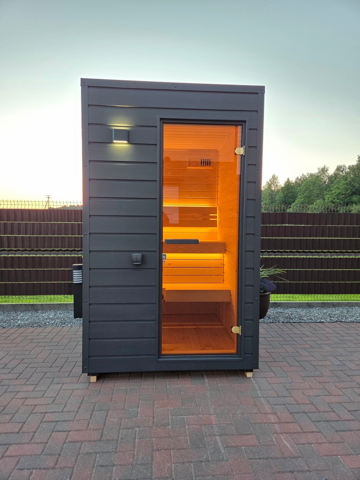 The cabin square on at dusk, the lit interior visible through the full height door