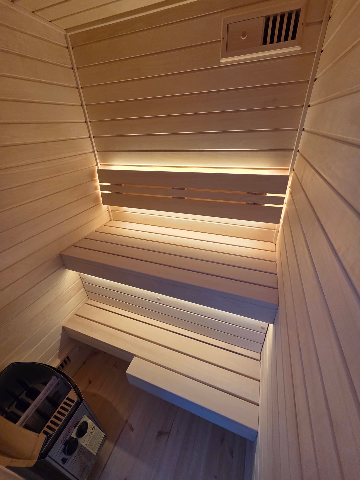 Looking down into the cabin at two pine benches under a lit backrest